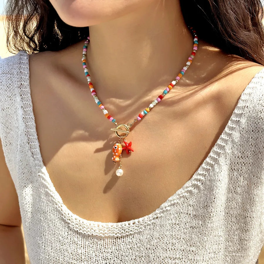 Collar de abalorios blanco con charm de pez cerámico, estrella de mar y perla, cierre OT dorado